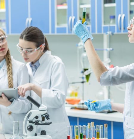 Female scientists working with reagents and digital tablet in chemical laboratory